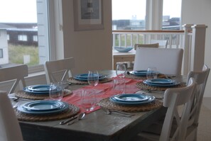 Une table à manger dressée pour quatre personnes, avec des assiettes bleues, des verres transparents et des couverts.