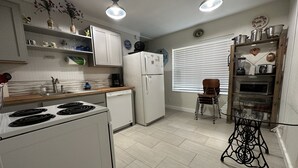 Una cucina moderna con elettrodomestici bianchi, un piano di lavoro in legno e un'area pranzo con una sedia e un tavolo.