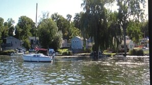 Un plan d’eau calme, avec un bateau amarré, entouré de maisons et d’arbres.