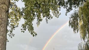 Une terrasse offrant une vue sur un lac, un arc-en-ciel et un bateau amarré au quai.