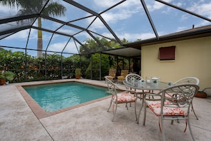 A covered outdoor area with a pool, seating, and potted plants.
