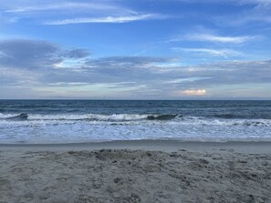 A beach with waves and a clear sky.