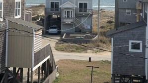 A two-story house with a balcony, located near a beach with the ocean in the background. - Spectacular Sound & Ocean Views, OBX 3BR2BA House, sleeps 8, dog friendly (Frisco)