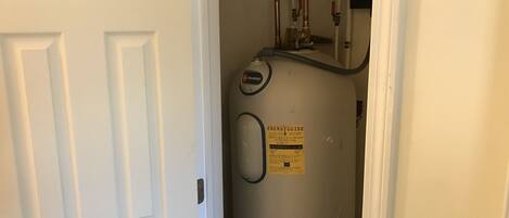 A water heater in a hallway with a white door.