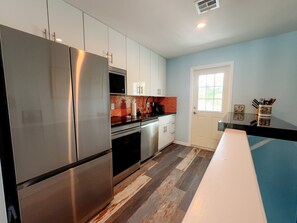 Een moderne keuken met roestvrijstalen apparatuur, witte kasten en een visgraatparketvloer.