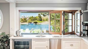 Une cuisine dotée d’une grande fenêtre offrant une vue imprenable sur un lac et des bateaux.