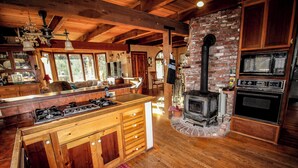 Une cuisine de style rustique avec un îlot central, une cheminée en briques et des meubles de rangement en bois.