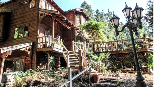 Une cabane en bois dotée d’un balcon, d’un escalier et d’une terrasse en bois.