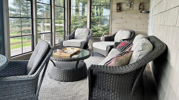 Un ambiente soleado con muebles de mimbre, ventanas amplias y vistas al exterior.