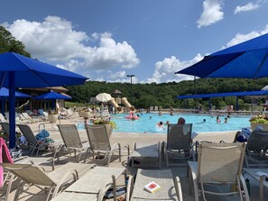 A pool area with lounge chairs and umbrellas, a slide, and a water play area.