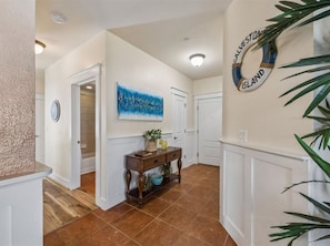 A hallway with a wooden console table, a painting, and a wall-mounted sign.