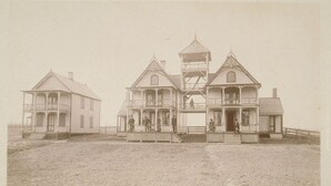 Un bâtiment historique à étages, doté d’une tour centrale et d’un porche avec des balustrades.