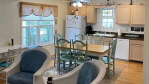 A modern kitchen with wooden cabinets, a dining area with wicker chairs, and a ceiling fan. - Perfect Key West Style - Golf -Tennis - Pet Friendly (Bethany Beach)