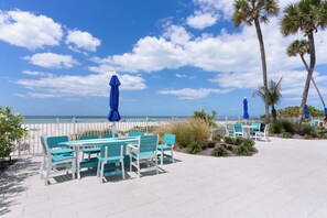 Une terrasse avec des sièges et des parasols, donnant sur une plage.
