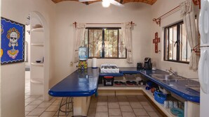 A kitchen with a blue countertop, a water dispenser, a stove, and a sink.