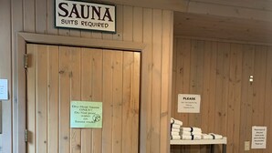 Una puerta de madera con un cartel que indica una sauna y otro cartel que solicita toallas.