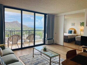 A room with a balcony, a bed, a desk, and a sofa. - Ocean View Upgraded Waikiki Banyan (Honolulu)