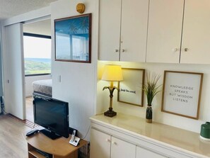 A hotel room with a bed, a desk with a computer, a lamp, and a view of the outdoors. - Ocean View Upgraded Waikiki Banyan (Honolulu)