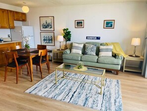 A living room with a dining area, a sofa, a coffee table, and a kitchen in the background. - Ocean View Upgraded Waikiki Banyan (Honolulu)