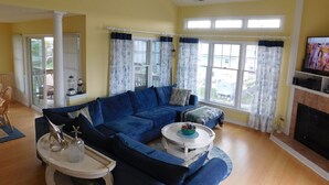 Een woonkamer met een blauwe modulaire bank, een witte salontafel en een open haard.