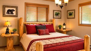 A wooden bed with a red and white bedspread, two bedside tables with lamps, and framed pictures on the walls.