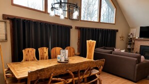 A dining area with a wooden table and chairs, a sofa, and a fireplace.