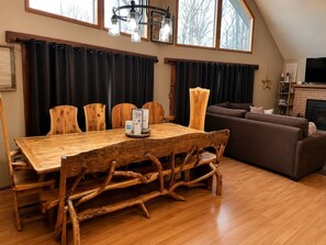 A dining area with a wooden table and chairs, a sofa, and a fireplace. - Spacious 5 BR/3 BA Pocono Chalet game room in the Hideout (lake ariel)
