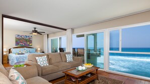 A spacious living room with a large sliding glass door leading to a balcony with ocean views. - Oceanfront Penthouse, As Close As You Can Stay To Ocean, Stunning Views, A/C! (Kailua-Kona)