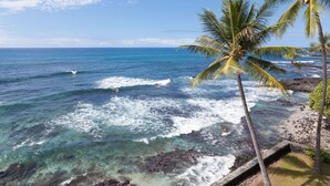 A beach with clear blue water, waves, and palm trees. - Oceanfront Penthouse, As Close As You Can Stay To Ocean, Stunning Views, A/C! (Kailua-Kona)