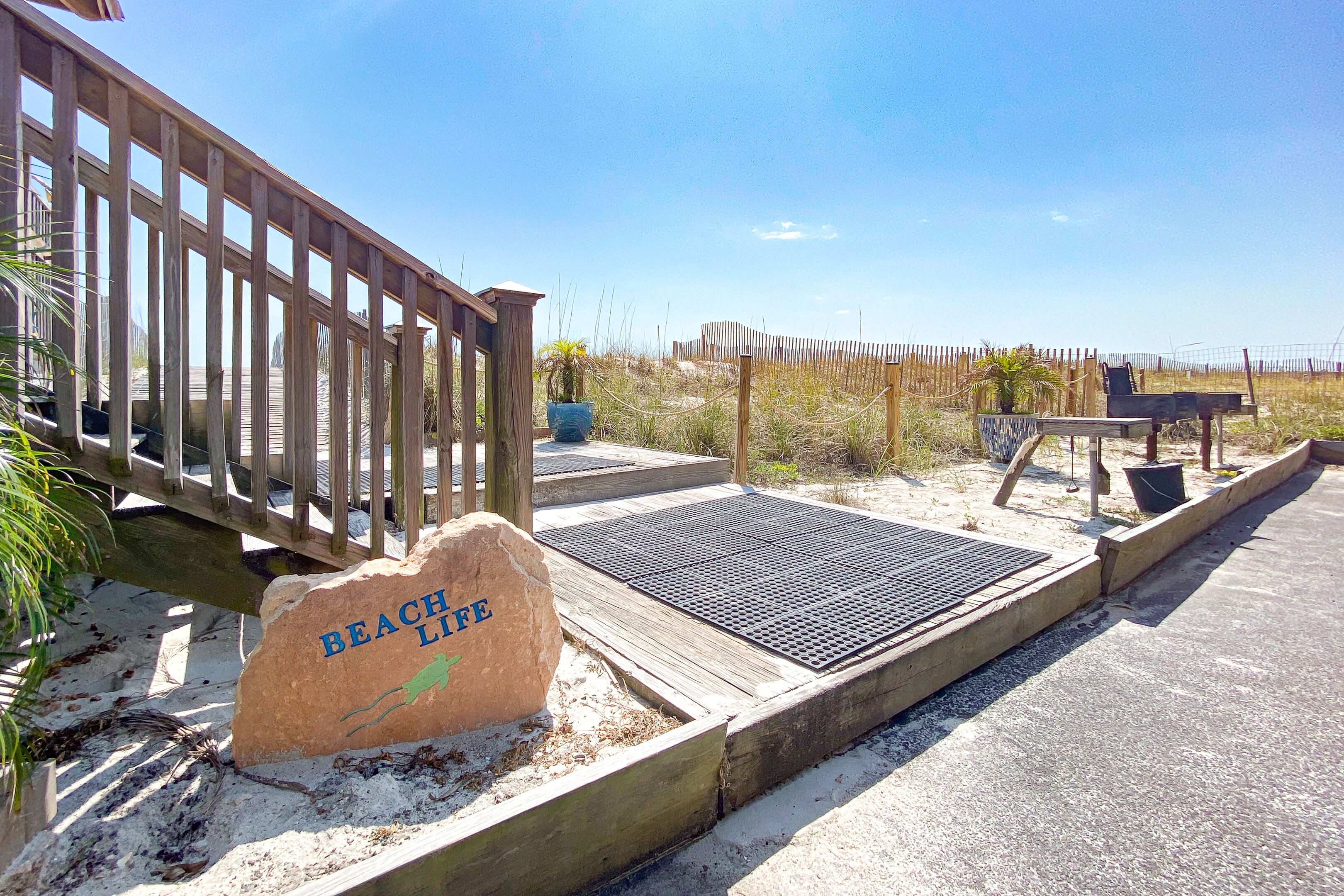 A wooden deck leading to a beach area with a sign reading "BEACH LIFE".
