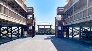 A covered parking area with a central gazebo and wooden structures on stilts.