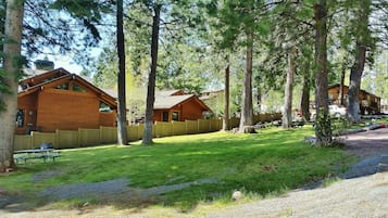 A lodge with wooden cabins, a picnic area, and a gravel path.