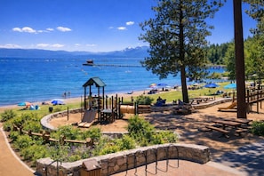 A park with a playground, picnic tables, and a view of the lake.