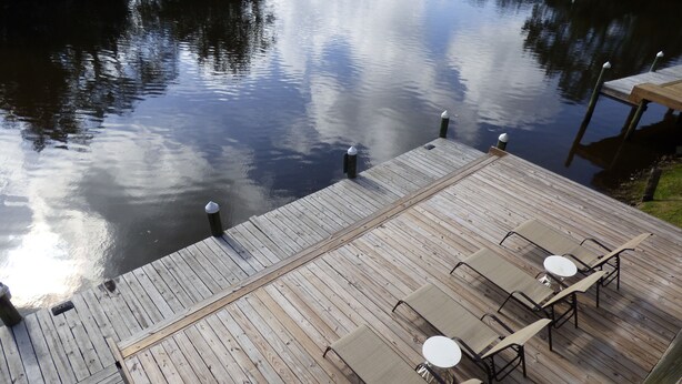 En træterrasse med et bord og stole, med udsigt over et roligt vandareal.