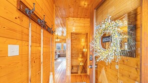 A wooden interior hallway with a wreath on the door, a coat rack, and a visible living area in the background. - Heavenly View Cabin (Sevierville)