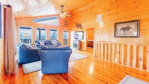A wooden interior with a ceiling fan, a sofa, and a framed picture on the wall. - Heavenly View Cabin (Sevierville)