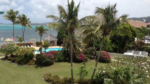Un complexe hôtelier tropical doté d’une piscine, de palmiers et offrant une vue sur l’océan.
