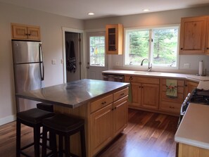 Enjoy cooking in this kitchen with a spacious island and bar stools, a sleek refrigerator, and warm cabinetry.