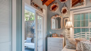 A bedroom with a bed, dresser, and a mirror. - Beachfront, Chic a si Cottage, original vintage Florida charm right on the Gulf (Indian Rocks Beach)