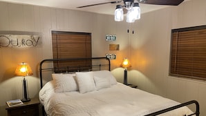 A neatly made bed with a metal frame, two bedside lamps, a wooden headboard, and a ceiling fan. - Quiet vacation house on forested property in Ouray (Ouray)