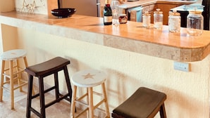 A kitchen with a bar area, wooden ceiling beams, and a ceiling fan. - Gorgeous, Spa-like 3BR with Island Elegance & Stunning Ocean Views (St Thomas)