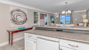 A modern kitchen with a granite countertop, white cabinetry, and a dining area with a view of the ocean. - Come on down! Great weather, comfortable furniture and beds! 
Best view! (Surfside Beach)
