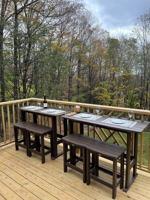 A wooden deck with a table and benches, surrounded by trees. - Spacious Three-level Home , Well-Furnished, Fun Playroom, Minutes to Mt. Snow (Wilmington)