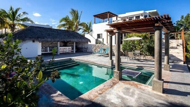 A modern pool area with a clear pool, lounge chairs, and a pergola structure. - Casa Torote, La Ventana (El Sargento)