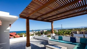 A rooftop terrace with a wooden pergola, outdoor seating, and a view of the sea and mountains. - Casa Torote, La Ventana (El Sargento)
