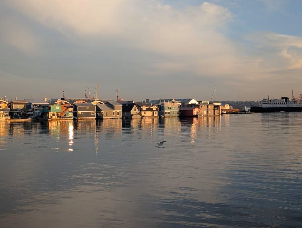 A waterfront area with floating houses and a large ship docked at the pier.