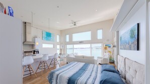 Une chambre moderne avec un lit, un coin repas et une vue sur la mer.