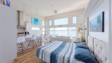 Une chambre moderne avec un lit, un coin repas et une vue sur la mer.