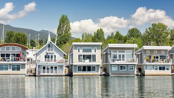 Une rangée de maisons flottantes dotées de plusieurs terrasses, de grandes fenêtres et, en arrière-plan, une étendue d’eau calme.