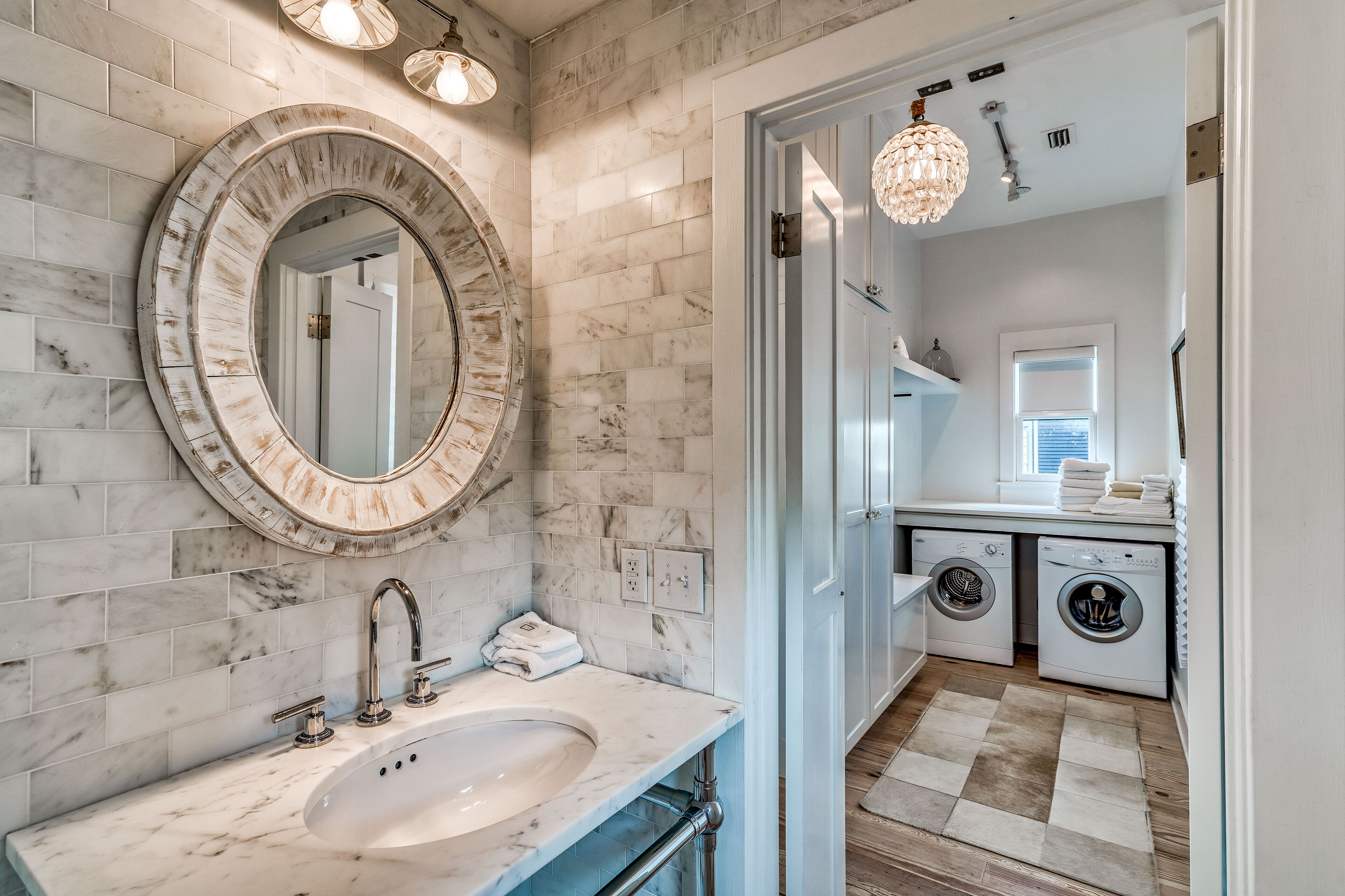 A bathroom with a marble sink, a large mirror, and a washing machine.